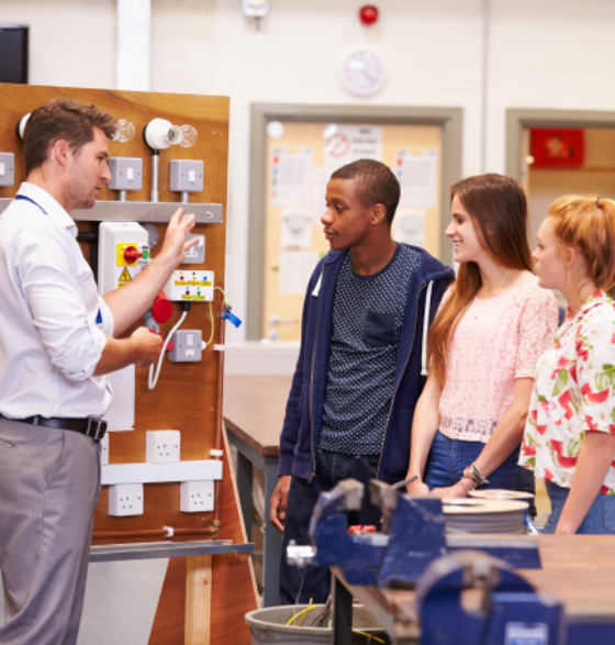 Ausbildung im Ausland: Ausbilder erklärt internationalen Auszubildenden eine elektrische Schaltung.