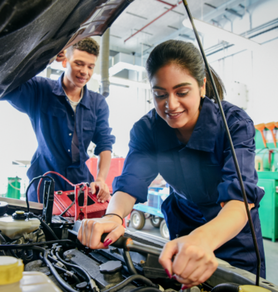 Auslandspraktikum während der Ausbildung: Auszubildende schrauben im Motorraum eines Autos.