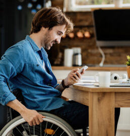 10 young-happy-entrepreneur-wheelchair-reading-message-smart-phone-while-working-home