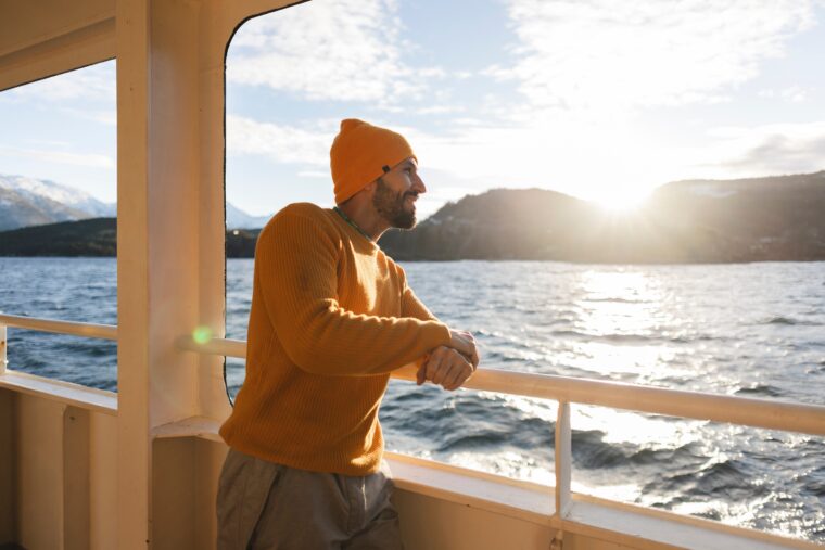 Traveller leaning on ferry, looking at the sea